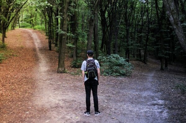 Homme dans une forêt. A gauche, la forêt éclairée. A droite, la forêt sombre.